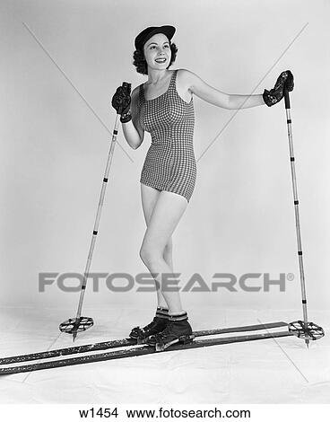 1930 1930S Woman Posing In Studio Wearing Bathing Suit Hat Gloves Skis Holding Ski Poles View Large Photo Image Picture - 1930 1930S Woman Posing In Studio Wearing Bathing Suit Hat Gloves Skis Holding Ski Poles . Fotosearch