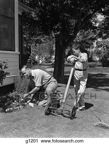 1930s 1940s 父 及び 息子 すること 庭仕事 男の子 ある 上に傾斜する 押し 芝刈機 人間がひざまずく 仕事 中に 花 ベッド ストックイメージ G11 Fotosearch