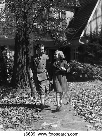 1930S 1940S Boy Girl Walking On Sidewalk Autumn Leaves Carrying School Books Wear Wool Coat Boy View Large Photo Image Stock Photo - 1930S 1940S Boy Girl Walking On Sidewalk Autumn Leaves Carrying School Books Wear Wool Coat Boy . Fotosearch