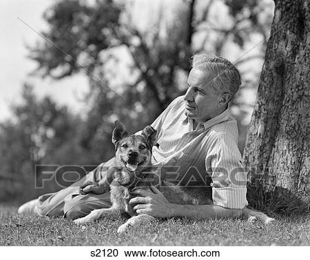1930S 1940S Elederly Man Lying Under A Tree With Dog Leisure Relax Retire Yard Grass Shade View Large Photo Image Stock Image - 1930S 1940S Elederly Man Lying Under A Tree With Dog Leisure Relax Retire Yard Grass Shade . Fotosearch