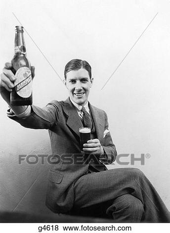 1930S 1940S Man Smiling At Camera Holding Up Huge Distorted Beer Bottle In One Hand And A Regular Size Glass Of Beer In Other View Large Photo Image Stock Photo - 1930S 1940S Man Smiling At Camera Holding Up Huge Distorted Beer Bottle In One Hand And A Regular Size Glass Of Beer In Other. Fotosearch