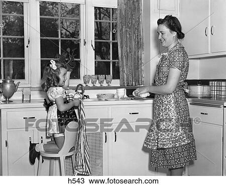 1930S 1940S Mother With Daughter Kneeling On Chair Helping With Washing & Drying Dishes In Kitchen View Large Photo Image Stock Image - 1930S 1940S Mother With Daughter Kneeling On Chair Helping With Washing & Drying Dishes In Kitchen . Fotosearch