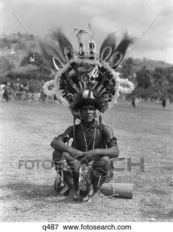 1930S 1940S Portrait Native Man In Elaborate Feathered Headdress Costume Sitting On Ground Port Moresby New Guinea View Large Photo Image Stock Photo - 1930S 1940S Portrait Native Man In Elaborate Feathered Headdress Costume Sitting On Ground Port Moresby New Guinea . Fotosearch