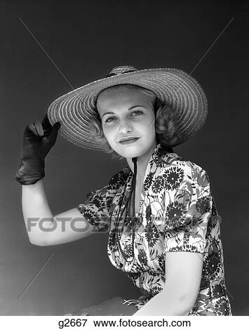 Stock Photo - 1930S 1940S Portrait Woman Straw Hat Floral Dress One Hand Up To Hat Gloves Fashion Beauty . Fotosearch