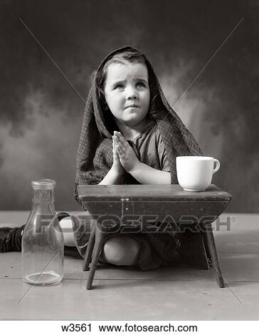 Stock Image - 1930S 1940S Sad Little Girl Shawl Over Hair Hands Praying. Fotosearch