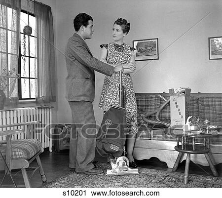 1930S 1940S Salesman In Suit Demonstrating Vacuum Cleaner By A Window In A Living Room To A Lady Wearing A Print Dress View Large Photo Image Stock Image - 1930S 1940S Salesman In Suit Demonstrating Vacuum Cleaner By A Window In A Living Room To A Lady Wearing A Print Dress. Fotosearch
