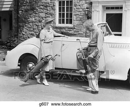 1930S 1940S Senior Couple Putting Golf Clubs In Convertible Car By Stone House View Large Photo Image Stock Photo - 1930S 1940S Senior Couple Putting Golf Clubs In Convertible Car By Stone House. Fotosearch