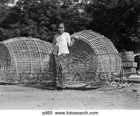 1930S 1940S Small Native Woman Standing By Two Large Japanese Fish Traps Fishing Baskets Batavia Java Indonesia View Large Photo Image Stock Image - 1930S 1940S Small Native Woman Standing By Two Large Japanese Fish Traps Fishing Baskets Batavia Java Indonesia. Fotosearch