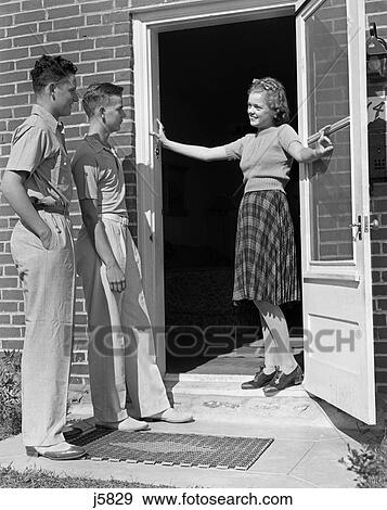 1930S 1940S Teen Girl Smiling Welcoming Two Boys At Front Door View Large Photo Image Stock Photo - 1930S 1940S Teen Girl Smiling Welcoming Two Boys At Front Door . Fotosearch