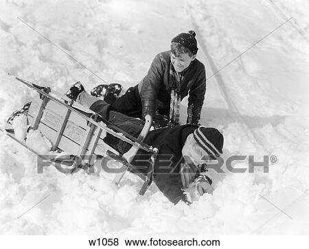 1930S 1940S Two Boys Laughing In Snow Just Fallen Off Of Sled That Is Turned On Its Side View Large Photo Image Stock Photo - 1930S 1940S Two Boys Laughing In Snow Just Fallen Off Of Sled That Is Turned On Its Side . Fotosearch