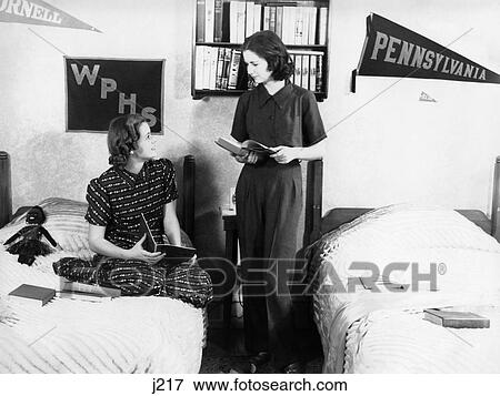 Stock Photo - 1930S 1940S Two Teen Girls Room Mates College School Dorm Room Talking Holding Books Study. Fotosearch