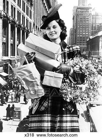 Stock Photo - 1930S 1940S Woman Arms Full Christmas Shopping Pacakages & Wreath Composite With City Street Scene . Fotosearch