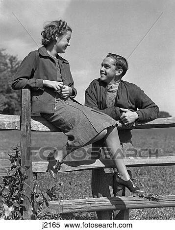 Stock Photography - 1930S 1940S Young Happy Teen Couple On Wooden Fence . Fotosearch