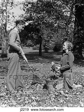 1930S 1940S Young Teen Couple Boy Girl Raking Autumn Leaves View Large Photo Image Stock Photo - 1930S 1940S Young Teen Couple Boy Girl Raking Autumn Leaves . Fotosearch
