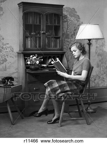 1930S 1940S Young Woman Teenage Sitting In A Chair Reading A Book By A