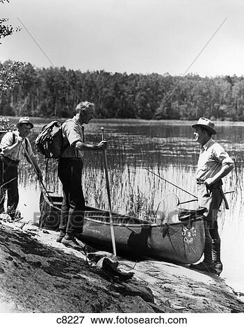1930S 3 Men Standing Beside Canoe On Lake Holding Fishing Gear Net Backpack Lake Of The Woods Ontario View Large Photo Image Stock Photo - 1930S 3 Men Standing Beside Canoe On Lake Holding Fishing Gear Net Backpack Lake Of The Woods Ontario . Fotosearch