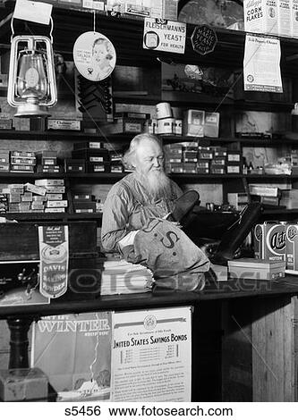 1930S Bearded Grocer Behind Counter In General Store Looking At Rubber Boots View Large Photo Image Stock Photograph - 1930S Bearded Grocer Behind Counter In General Store Looking At Rubber Boots . Fotosearch