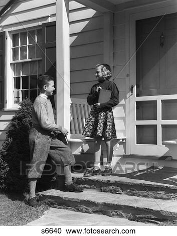 1930S Boy In Knickers Hold School Books Talking To Girl Standing On Porch Of House Teen Flirt Puppy Love Childhood Sweetheart View Large Photo Image Stock Image - 1930S Boy In Knickers Hold School Books Talking To Girl Standing On Porch Of House Teen Flirt Puppy Love Childhood Sweetheart. Fotosearch
