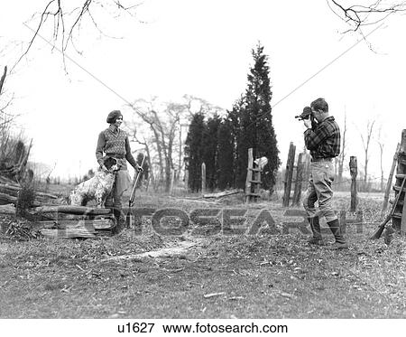 1930S Couple Both Wearing Jodhpurs And Boots Woman Is Posing With Bird Dog & Shotgun The Man Is Shooting Movies View Large Photo Image Stock Photo - 1930S Couple Both Wearing Jodhpurs And Boots Woman Is Posing With Bird Dog & Shotgun The Man Is Shooting Movies. Fotosearch
