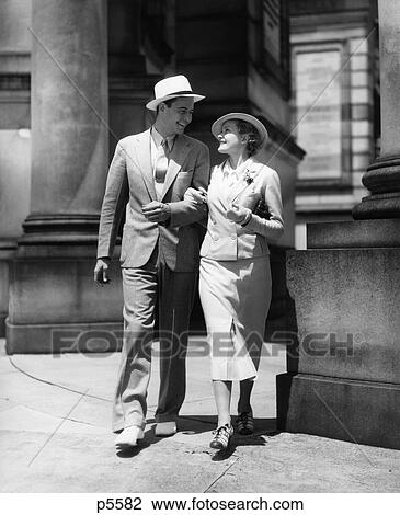 Stock Image - 1930S Couple In Suits And Hats Walking Arm In Arm . Fotosearch