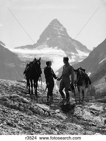1930S Couple Man Woman Holding Hands Standing With Horses In Mountains Western Mt. Assiniboine Canada View Large Photo Image Picture - 1930S Couple Man Woman Holding Hands Standing With Horses In Mountains Western Mt. Assiniboine Canada . Fotosearch
