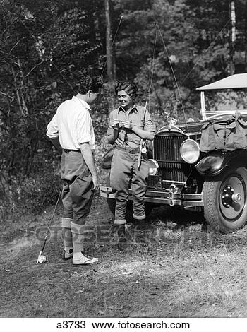 Stock Image - 1930S Couple Man Woman In Fishing Gear Holding Poles Standing In Front Of Car . Fotosearch