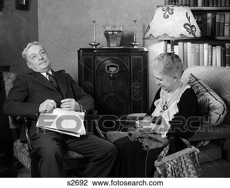 1930S Elderly Couple Sitting In Living Room Listening To Radio Woman Knitting Man With Newspaper In Lap View Large Photo Image Stock Image - 1930S Elderly Couple Sitting In Living Room Listening To Radio Woman Knitting Man With Newspaper In Lap . Fotosearch