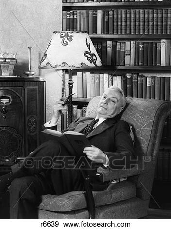 1930S Elderly Man In Armchair Relaxing With Book & Pipe & Listening To Radio View Large Photo Image Stock Photo - 1930S Elderly Man In Armchair Relaxing With Book & Pipe & Listening To Radio . Fotosearch