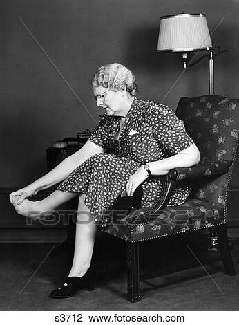 1930S Elderly Woman Sitting Chair Rubbing Sore Tired Feet Toes View Large Photo Image Stock Image - 1930S Elderly Woman Sitting Chair Rubbing Sore Tired Feet Toes . Fotosearch