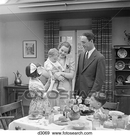 Stock Photo - 1930S Family Of 5 In Dining Room Mother Standing Holding Baby . Fotosearch