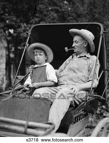 Stock Photo - 1930S Farm Boy & Grandfather In Overalls & Straw Hats Sitting In Small Buggy . Fotosearch