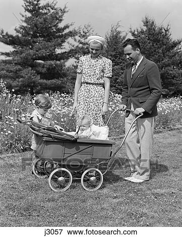 1930S Father Pushing Baby Carriage In Grass With Mother & Son Beside Him View Large Photo Image Stock Photo - 1930S Father Pushing Baby Carriage In Grass With Mother & Son Beside Him . Fotosearch