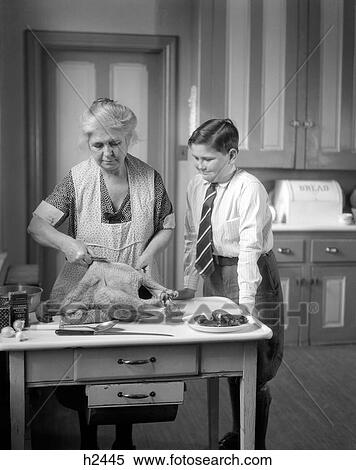 1930S Grandmother In Apron Preparing A Turkey In The Kitchen While Grandson In Dress Shirt Tie & Knickers Watches View Large Photo Image Stock Photography - 1930S Grandmother In Apron Preparing A Turkey In The Kitchen While Grandson In Dress Shirt Tie & Knickers Watches . Fotosearch