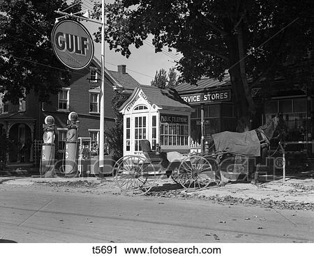 1930S Horse & Empty Buggy Tied To Pole Outside Of Gulf Service Station Next To Fancy Wooden Phone Booth With Shingled Roof View Large Photo Image Stock Image - 1930S Horse & Empty Buggy Tied To Pole Outside Of Gulf Service Station Next To Fancy Wooden Phone Booth With Shingled Roof. Fotosearch