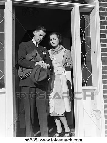 1930S Husband Wife Stand In Open Door Man Going To Work Checking Watch Holding Briefcase Hat In Hand View Large Photo Image Stock Photography - 1930S Husband Wife Stand In Open Door Man Going To Work Checking Watch Holding Briefcase Hat In Hand . Fotosearch