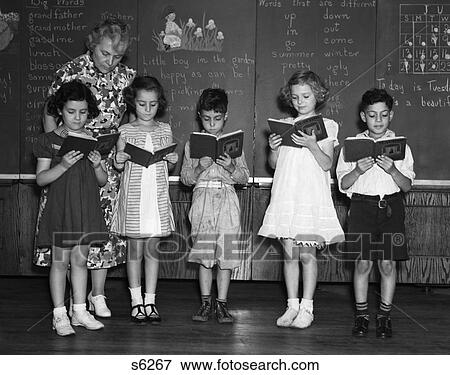 1930S Line-Up Of 5 Elementary School Students In Front Of Blackboard Reading Books With Teacher Looking On View Large Photo Image Stock Photo - 1930S Line-Up Of 5 Elementary School Students In Front Of Blackboard Reading Books With Teacher Looking On . Fotosearch