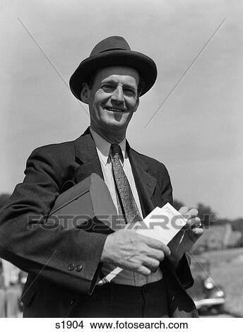 1930S Man In Suit & Hat With Lunch Pail Under Arm Holding Envelope With Paycheck View Large Photo Image Picture - 1930S Man In Suit & Hat With Lunch Pail Under Arm Holding Envelope With Paycheck . Fotosearch