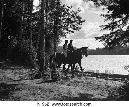 1930S Man & Woman Riding Horses Through Wooded Area Along Side Of Lake View Large Photo Image Stock Image - 1930S Man & Woman Riding Horses Through Wooded Area Along Side Of Lake . Fotosearch