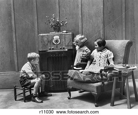 1930s Pair Of Girls Boy Sitting In Living Room Listening To Radio Stock Image