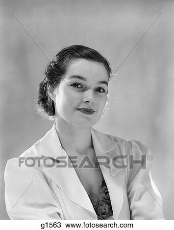 Stock Image - 1930S Portrait Of Young Brunette Woman Looking At Camera Half Smiling Fashion Beauty Wearing White Jacket With Lapels . Fotosearch