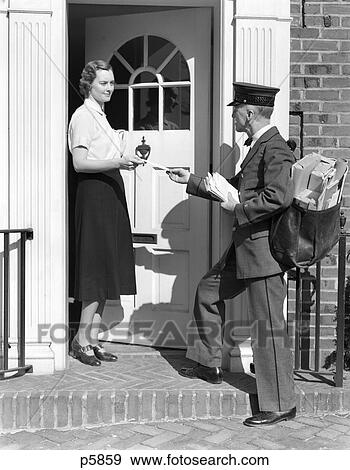 Stock Photo - 1930S Postman Giving A Letter To A Woman In The Doorway Of A Home Colonial Brick Step Brass Door . Fotosearch