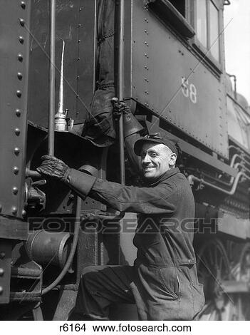 1930S Railroad Worker In Coveralls Hat Goggles & Gloves Climbing Up Onto Train View Large Photo Image Picture - 1930S Railroad Worker In Coveralls Hat Goggles & Gloves Climbing Up Onto Train . Fotosearch