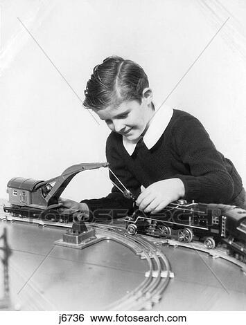 Stock Photograph - 1930S Smiling Boy Wearing A Sweater With White Shirt Collar Playing With Crane Car And Locomotive Of Model Train Set. Fotosearch