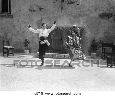 Stock Photograph - 1930S Smiling Couple Dressed In Spanish Folkloric Costumes & Playing Castanets Dancing The Flamenco . Fotosearch