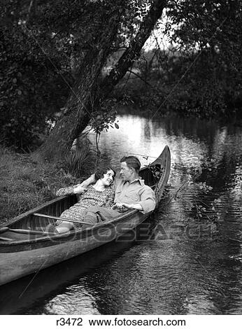 1930S Smiling Couple Reclining Canoe Bank Stream Woman Dress The Man Sport Shirt Jodhpurs Grass Trees Water View Large Photo Image Stock Image - 1930S Smiling Couple Reclining Canoe Bank Stream Woman Dress The Man Sport Shirt Jodhpurs Grass Trees Water. Fotosearch