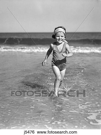 1930S Smiling Little Girl Running Out Of Surf At Beach View Large Photo Image Stock Photograph - 1930S Smiling Little Girl Running Out Of Surf At Beach . Fotosearch