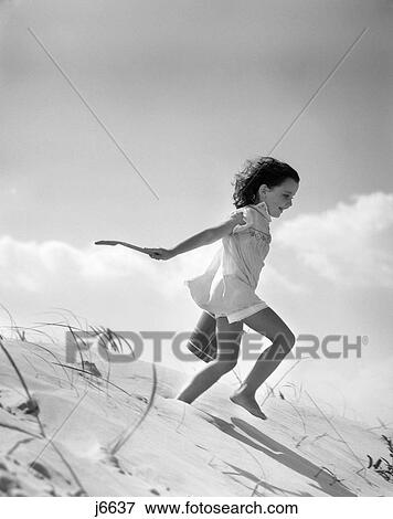 1930S Smiling Little Girl Shorts Outfit Carrying Sand Pail Shovel Running Down Dune View Large Photo Image Stock Photo - 1930S Smiling Little Girl Shorts Outfit Carrying Sand Pail Shovel Running Down Dune . Fotosearch