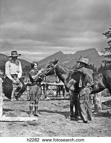 1930S Two Cowboys & A Woman Grooming A Horse Near The Corral The Standing Cowboy Is Wearing Batwing Chaps View Large Photo Image Stock Image - 1930S Two Cowboys & A Woman Grooming A Horse Near The Corral The Standing Cowboy Is Wearing Batwing Chaps . Fotosearch