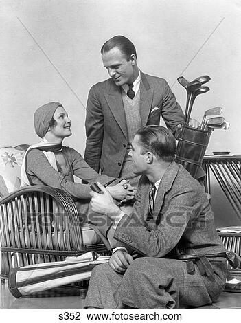 Stock Image - 1930S Two Men One Woman Golf Clubs And Bag Smiling Talking Sitting Bamboo Chair Man Smoking Pipe. Fotosearch