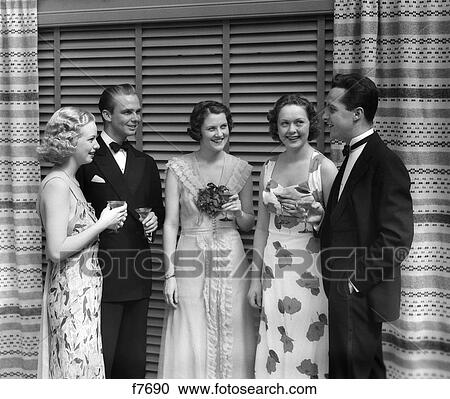 Stock Image - 1930S Two Men Three Women At Formal Cokctail Party Talking Holding Martinis Indoor . Fotosearch